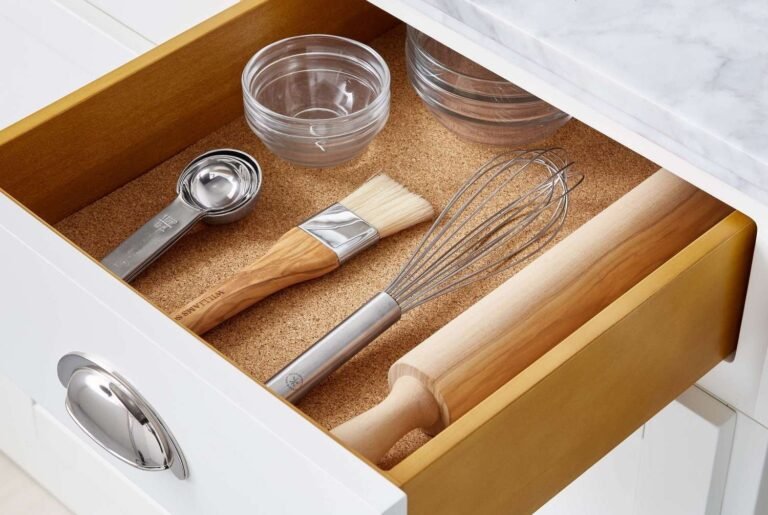 Roll of grey kitchen cabinet shelf liner unrolled on a white shelf